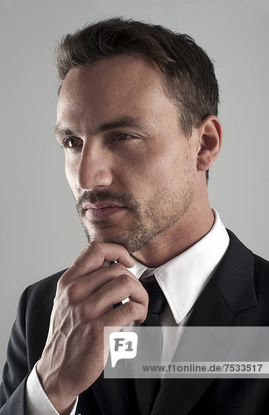 Young businessman wearing a suit with his hand on his chin  pensive  portrait