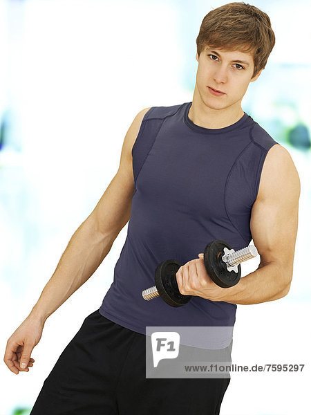 Junger Mann beim Krafttraining mit Kurzhantel  muskulös