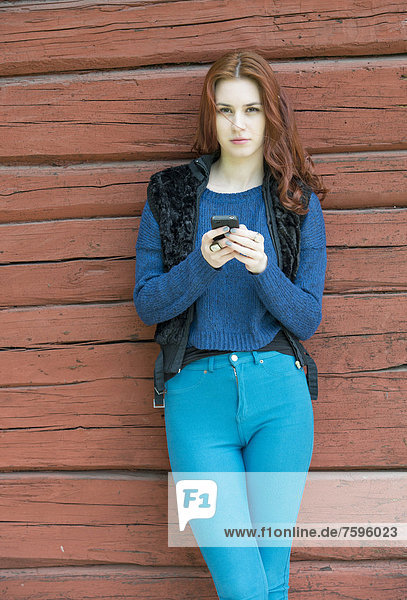Beatiful young woman with red hair holding a mobile phone