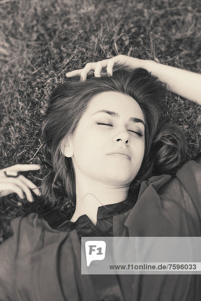 Young woman with closed eyes lying on grass