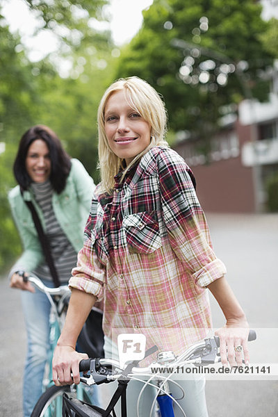 Frauen stehen auf Fahrrädern auf der Stadtstraße