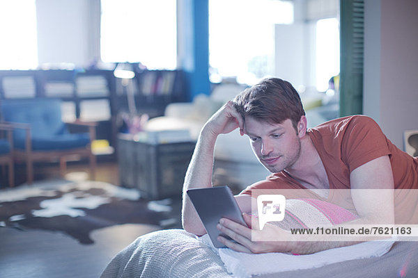 Man using digital tablet on bed