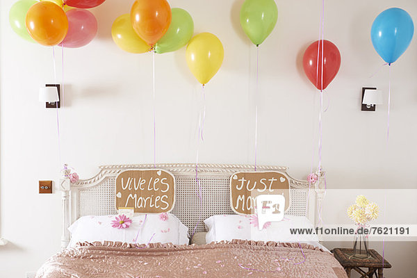 Dekoriertes Ehebett mit Luftballons und Schildern
