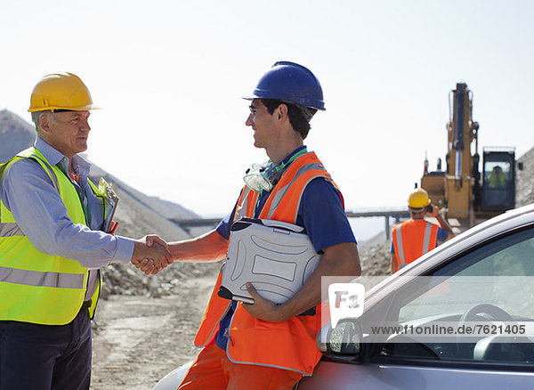 Worker and businessman shaking hands in quarry