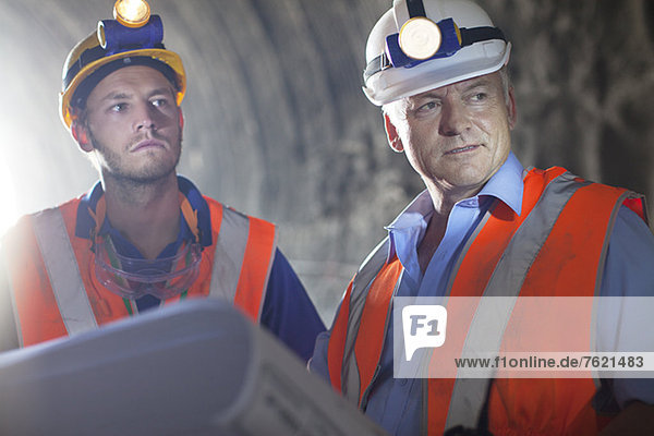 Arbeiter und Geschäftsmann mit Bauplänen im Tunnel