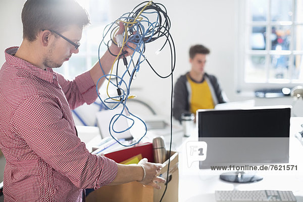 Businessman untangling cords in office