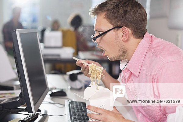 Businessman eating Chinese food at desk