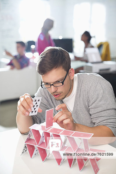 Businessman making house of cards in office