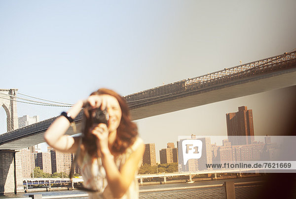 Woman taking pictures by urban bridge