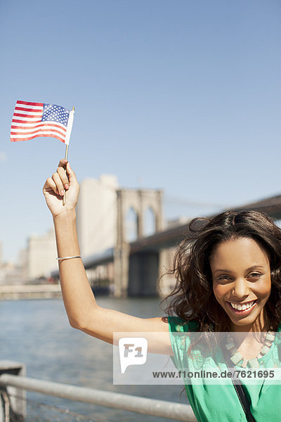 Frau winkt mit amerikanischer Flagge an der Hafenpromenade
