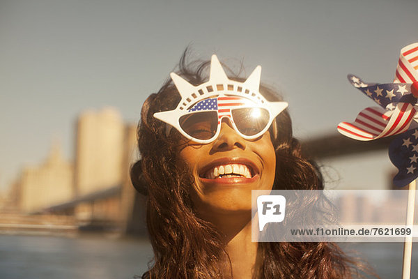Woman with novelty sunglasses and pinwheel by urban bridge