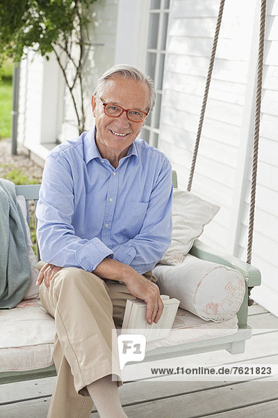 Lächelnder Mann sitzend auf der Veranda-Schaukel