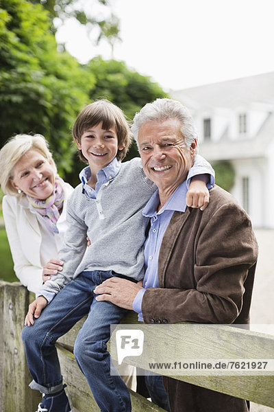 Couple and grandson smiling by wooden fence