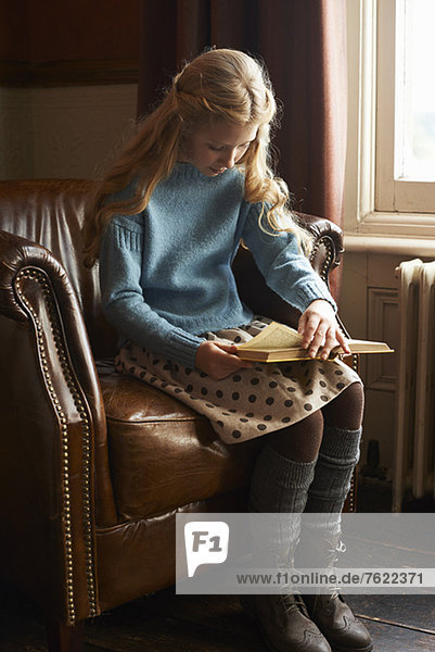 Girl reading book in armchair
