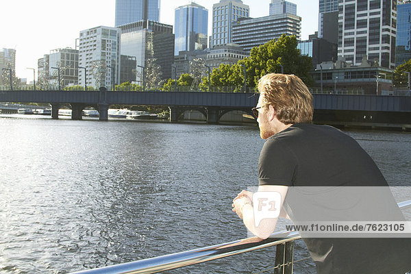 Mann mit Blick auf den städtischen Fluss auf der Brücke