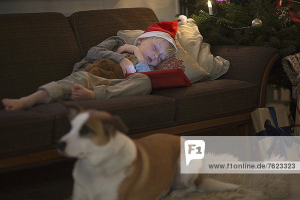 Junge mit Nikolausmütze schläft auf dem Sofa
