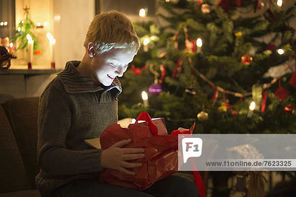 Lächelnder Junge eröffnet Weihnachtsgeschenk