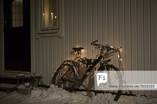 Bicycle with fairy lights in snow