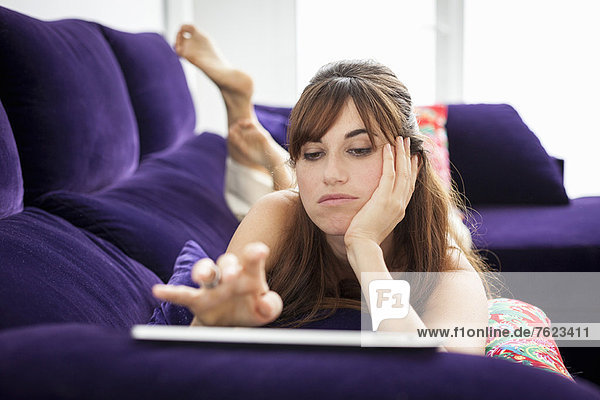 Frau mit Tablet-Computer auf dem Sofa