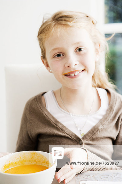 Lächelndes Mädchen hält eine Schüssel Suppe.