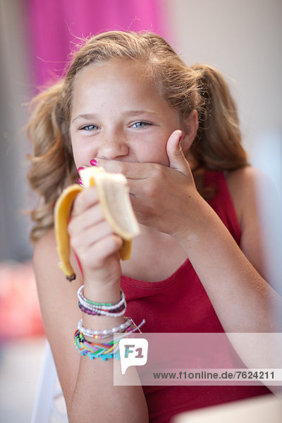 Smiling girl eating banana