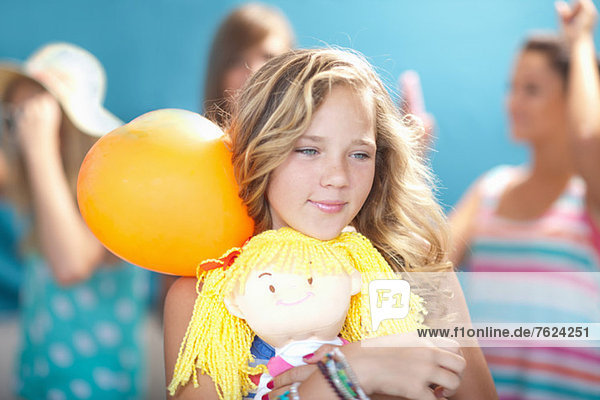 Lächelndes Mädchen mit Ballon und Puppe