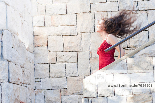 Frau klettert Steintreppe im Freien