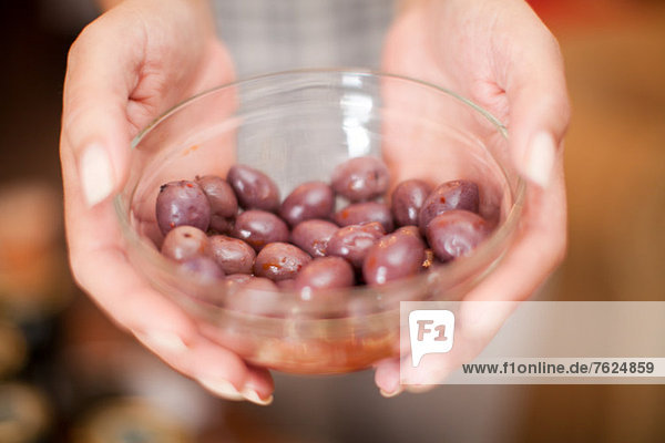 Frau hält Schale mit Oliven im Lebensmittelgeschäft