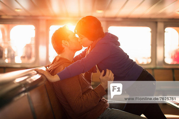 Couple kissing on ferry at sunset