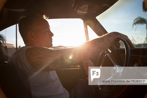 Man driving vintage car at sunset