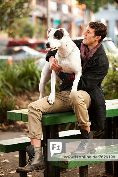 Mann sitzend mit Hund auf Picknicktisch