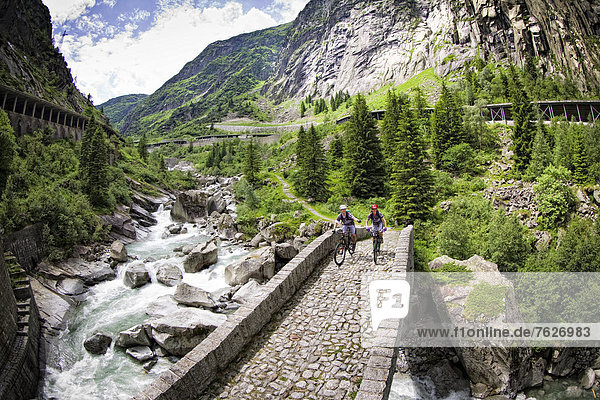 Two mountain bikers crossing a bridge  Andermatt  Switzerland