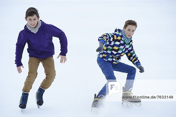 Zwei Jungen laufen Schlittschuh auf einem gefrorenen See