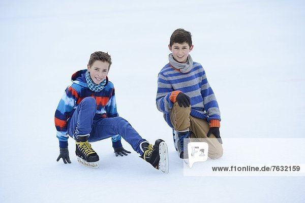 Zwei Jungen mit Schlittschuhen auf einem gefrorenen See