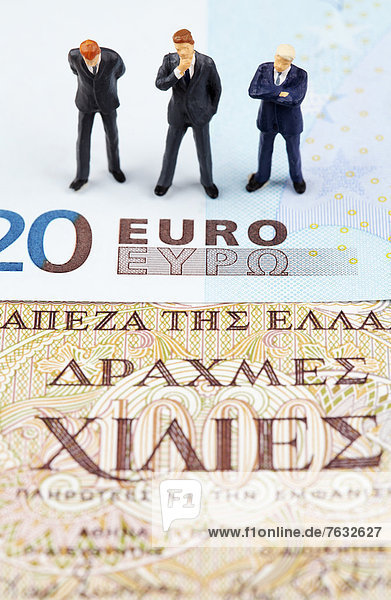 Miniatur-Figuren von Geschäftsleuten auf Euro- und Drachmen-Banknoten
