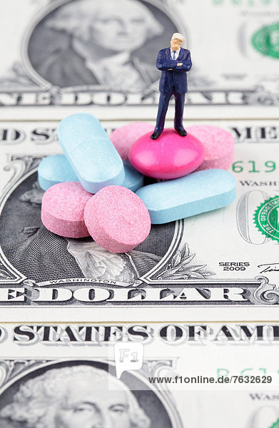 Miniatur-Figur des Geschäftsmannes im Stand auf Pillen auf einem Dollar-Schein