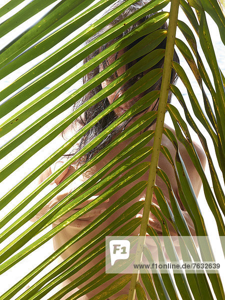 Frau  45  hinter Palmenblatt  Punta Uva  Puerto Viejo de Talamanca Costa Rica  Zentralamerika