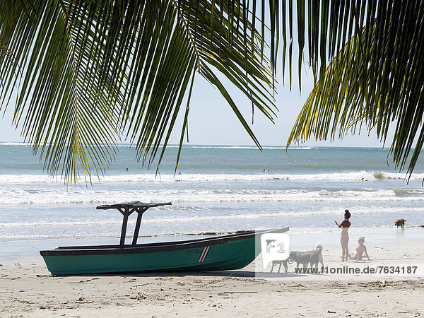 Boot  Costa Ricanerinnen und Hunde am Strand  Playa Samara  Nicoya-Halbinsel  Costa Rica  Zentralamerika