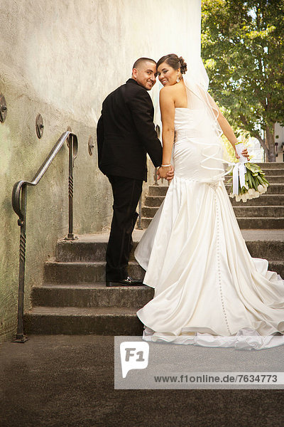 Hispanic bride and groom walking up steps