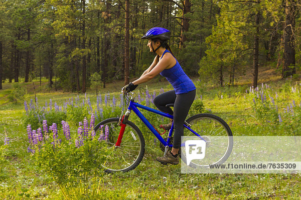 Chinese woman riding mountain bike in meadow