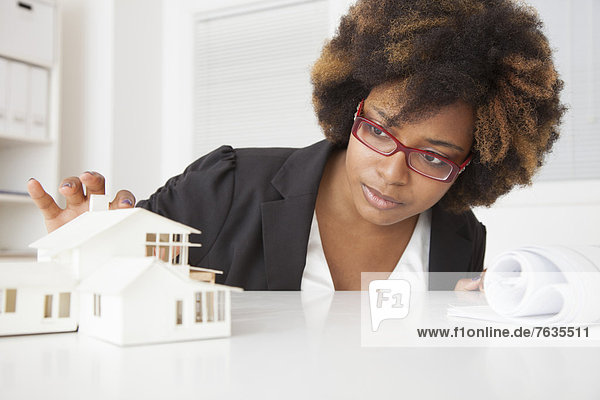 African American businesswoman working on model of house