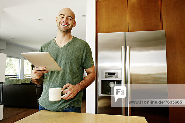 Hispanic man using tablet computer in kitchen