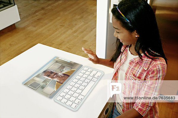 Girl waving at mother in computer in table