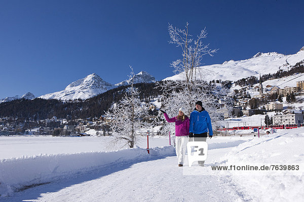 Frau Winter Mann gehen Weg See wandern Kanton Graubünden Wanderweg trekking Wintersport