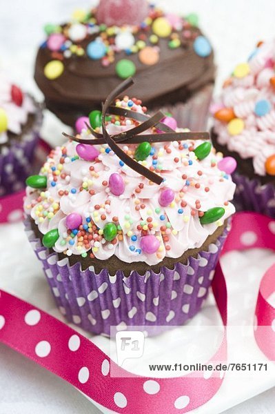 Zwei Cupcakes mit rosa Buttercreme  Schokoladencreme und Süssigkeiten