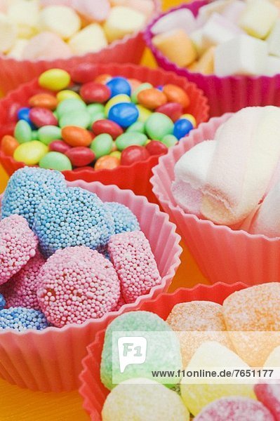 Verschiedene Süssigkeiten: Geleebonbons  Schokolinsen und Marshmallows in bunten Plastikschälchen