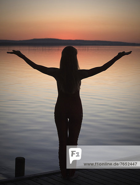 Frau Sonnenuntergang See Yoga Gegenlicht Pose