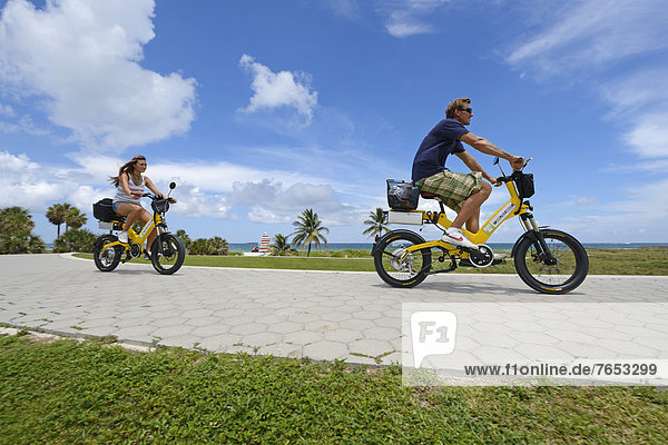 Couple riding electric bicycles  South Pointe Park  South Beach  Miami  Florida  USA