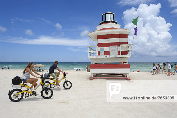 Couple riding electric bicycles  Watchtower  The Jetty  Miami Rescue Tower  South Beach  Miami  USA