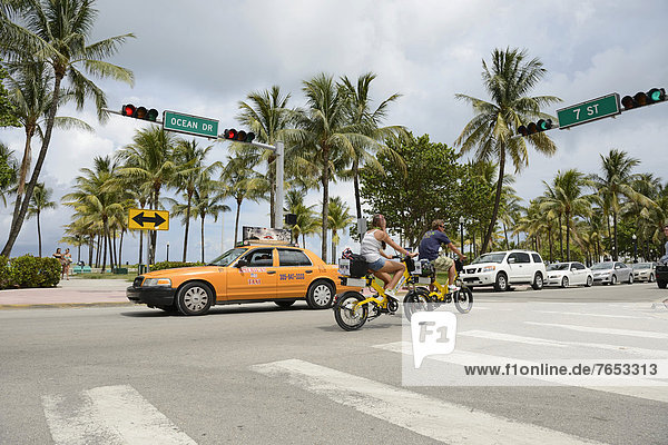 Couple riding electric bicycles  Ocean Drive  South Beach  Miami  Florida  USA